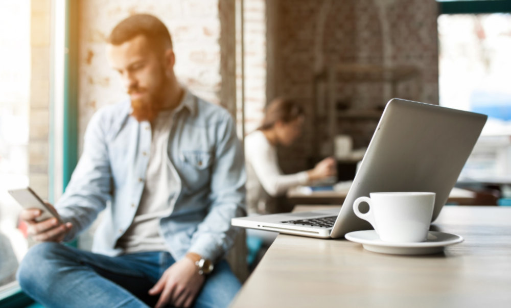 Datenschutz beim Arbeiten in öffentlichen Bereichen: Mann arbeitet im Café an seinem Laptop