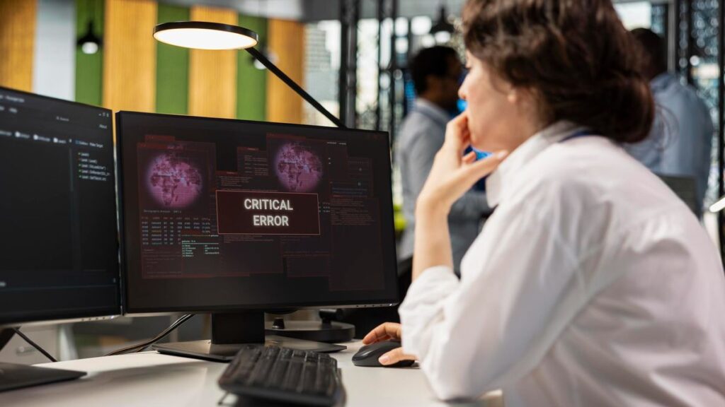 Meldepflicht nach dem Cyber Resilience Act: IT-Mitarbeiterin sieht eine kritische Fehlermeldung auf dem Bildschirm